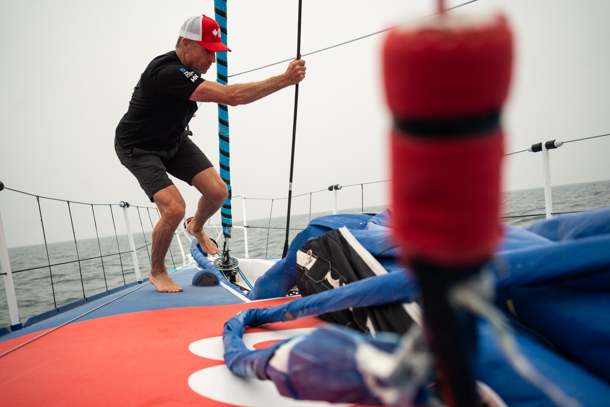 Man at the front of a boat, holding a rope in rough conditions